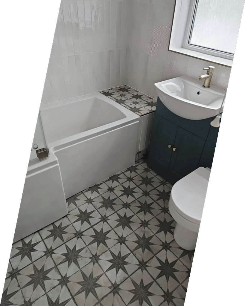 Modern bathroom with a white bathtub, geometric star-patterned floor tiles, a white sink with a gold faucet on a blue vanity, and a toilet.